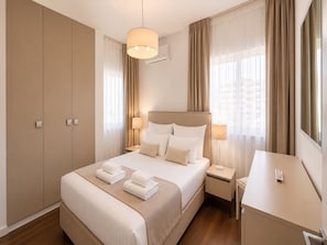 Habitación de hotel con una cama grande, un escritorio, un armario y una lámpara colgante.