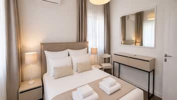 Una habitación de hotel con cama, lámparas de noche, escritorio, espejo y aire acondicionado.