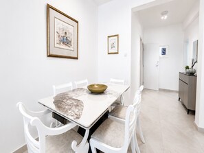 Un comedor con una mesa de mármol, sillas blancas y un cuenco dorado como centro de mesa.