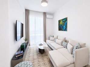 Ein modernes Wohnzimmer mit einer Couch, einem Couchtisch, einem Flachbildfernseher und einem Gemälde an der Wand.