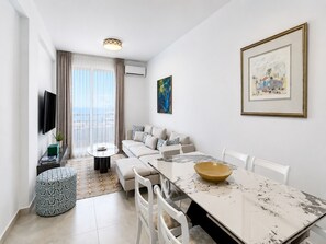 Een moderne woonkamer met een bank, eettafel, stoelen, een televisie en kunstwerken aan de muren.