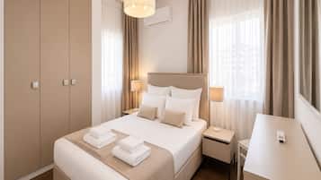 Una habitación de hotel con cama, lámparas de noche, escritorio y armario.