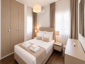 Ein Hotelzimmer mit Bett, Nachttischlampen, Schreibtisch und Kleiderschrank.