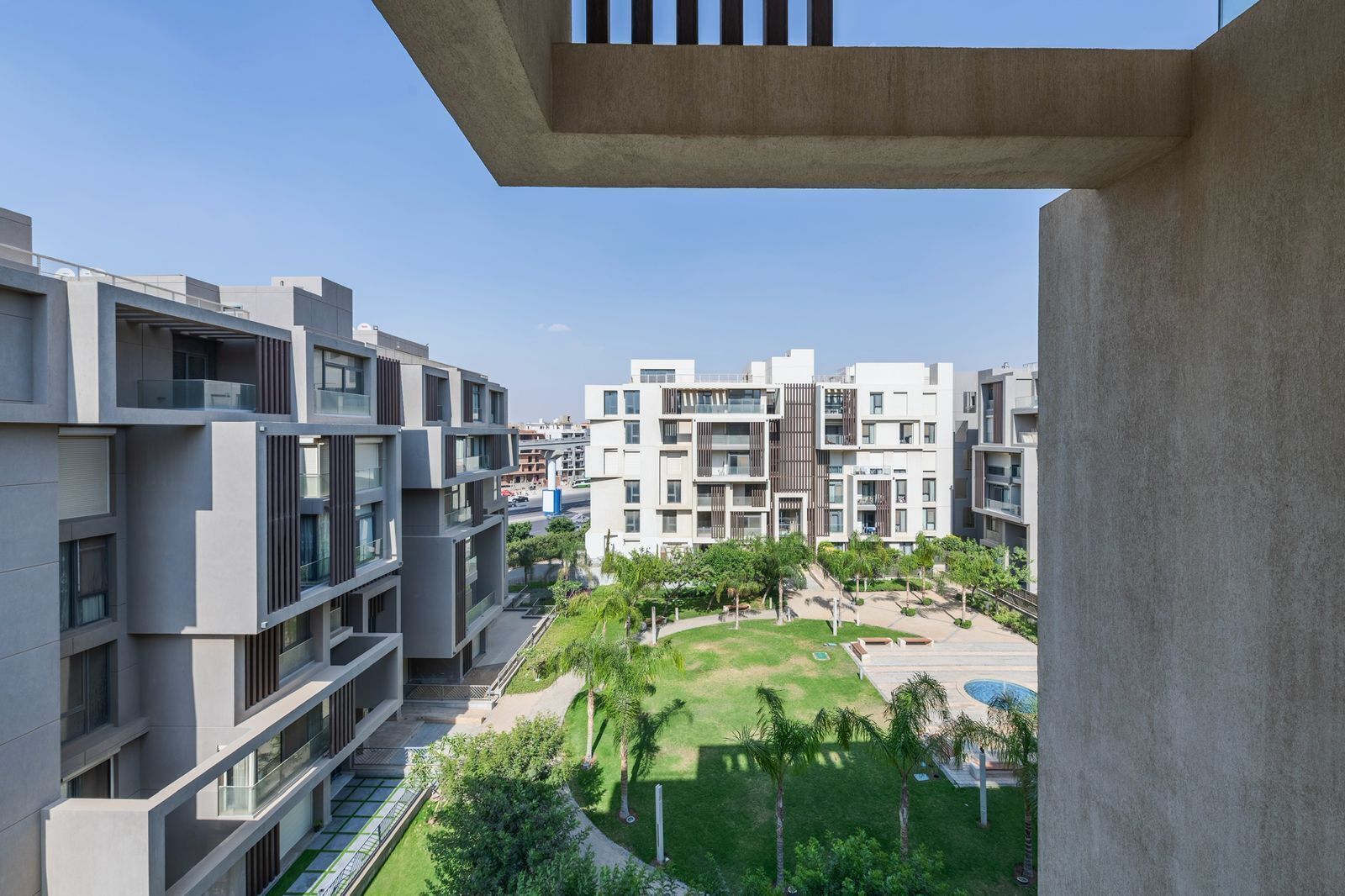 A modern apartment complex with multiple buildings, balconies, and a well-maintained courtyard with greenery.