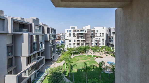 A modern apartment complex with multiple buildings, balconies, and a well-maintained courtyard with greenery. - Sodic Eastown  Panoramic EDNC View + Monorail (Cairo Governorate)