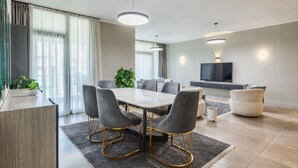 A modern living room with a dining area, a flat-screen TV, and a large window with curtains. - Sodic Eastown  Panoramic EDNC View + Monorail (Cairo Governorate)