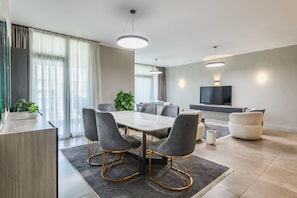 A modern living room with a dining area, a flat-screen TV, and a large window with curtains. - Sodic Eastown  Panoramic EDNC View + Monorail (Cairo Governorate)