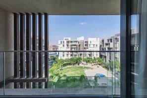 A balcony with a view of a modern apartment complex, a grassy area, and a pool. - Sodic Eastown  Panoramic EDNC View + Monorail (Cairo Governorate)