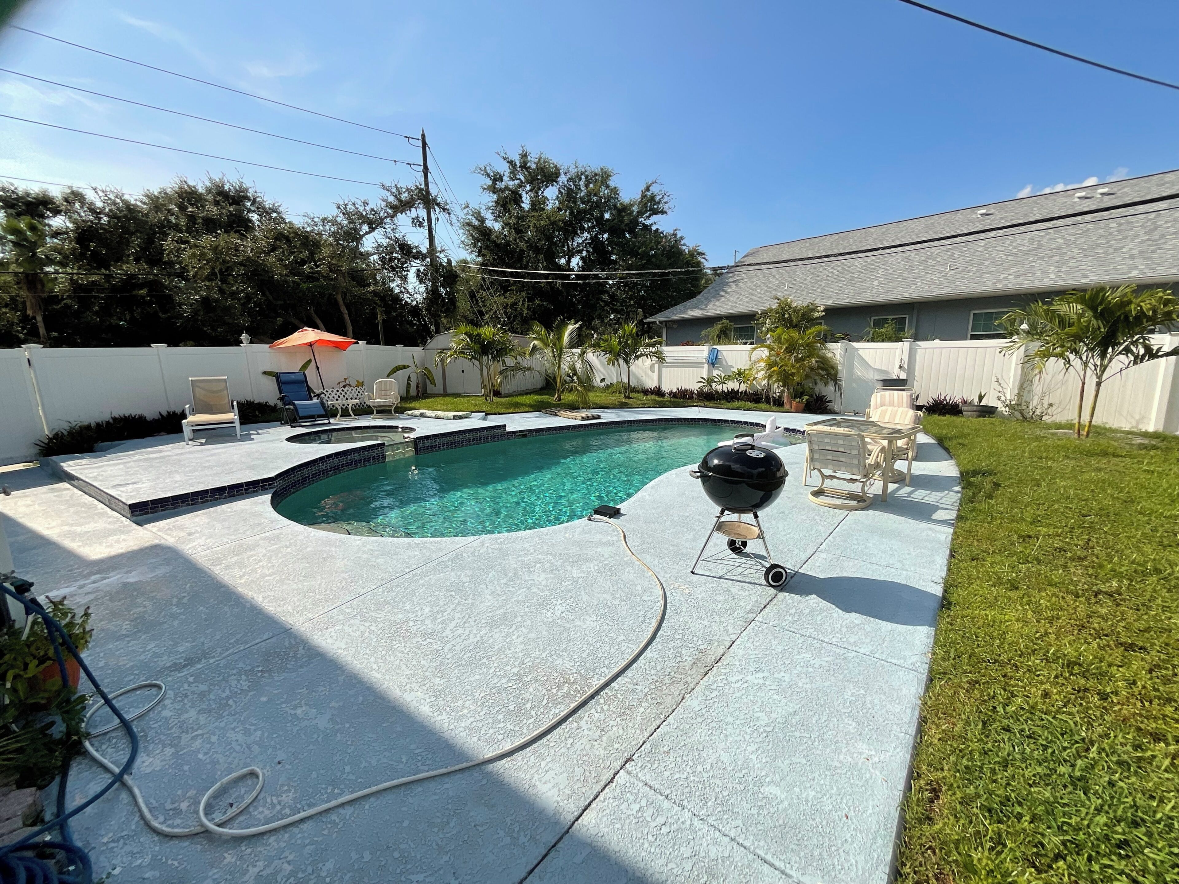 A backyard with a swimming pool, a grill, and outdoor furniture.