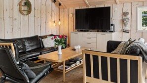 Ett mysigt vardagsrum med en svart lädersoffa, ett träbord och en bokhylla.