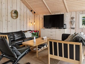 Ein gemütliches Wohnzimmer mit einem schwarzen Ledersofa, einem Holztisch und einem Bücherregal.