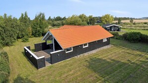 En modern stuga byggd av trä, med ett sluttande tak, en veranda och en liten tillbyggnad.