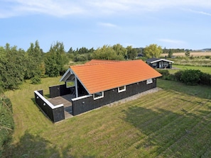 Eine moderne Holzhütte mit Satteldach, einer Terrasse und einem kleinen Anbau.