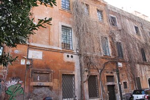 Ein mehrgeschossiges Gebäude mit vergitterten Fenstern, Graffiti und Ranken an der Fassade.