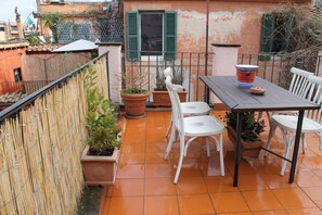 Eine Außenpatio mit Tisch und Stühlen, Kübelpflanzen und Blick auf Gebäude im Hintergrund.