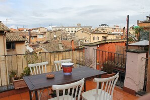 Eine Terrasse mit Tisch und Stühlen, einem Blumentopf und Blick auf die Stadt.