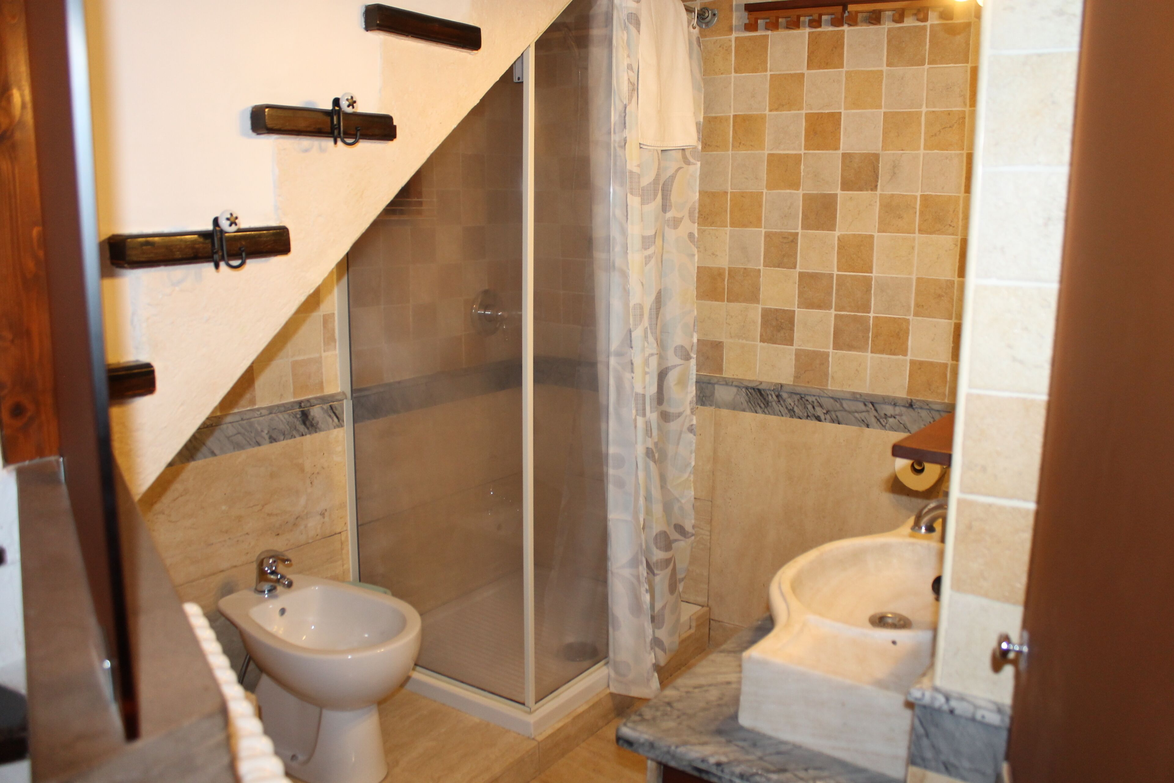 Een badkamer met een douche, toiletbrons en wastafel.