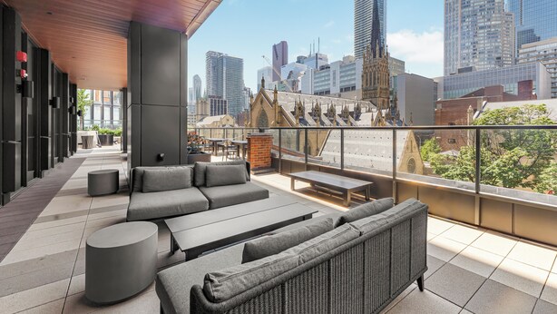 A rooftop terrace with modern seating, a view of the city skyline, and a historic building in the background. - Saint Suites - Penthouse 2Bed+2Bath High Rise Condo (Toronto)