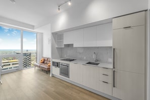 A modern kitchen with a large window, a sofa, and a view of the city.