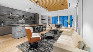 A modern kitchen with marble countertops, a wooden ceiling, and a dining area with a blue curtain backdrop. - Saint Suites - Penthouse 2Bed+2Bath High Rise Condo (Toronto)