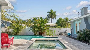 Piscina com hidromassagem, cercada por vegetação e móveis de jardim.