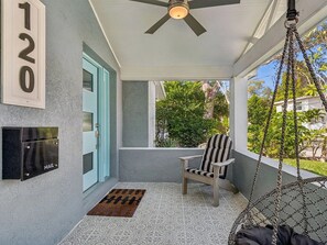 A porch with a mailbox, a door, a chair, and a hanging swing.