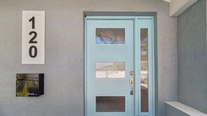 Uma porta azul clara com uma abertura para correspondência e uma placa com o número 120 na parede.