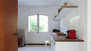 Eine Küche mit Fenster, Heizkörper, einem roten Gerät und einem Hocker.