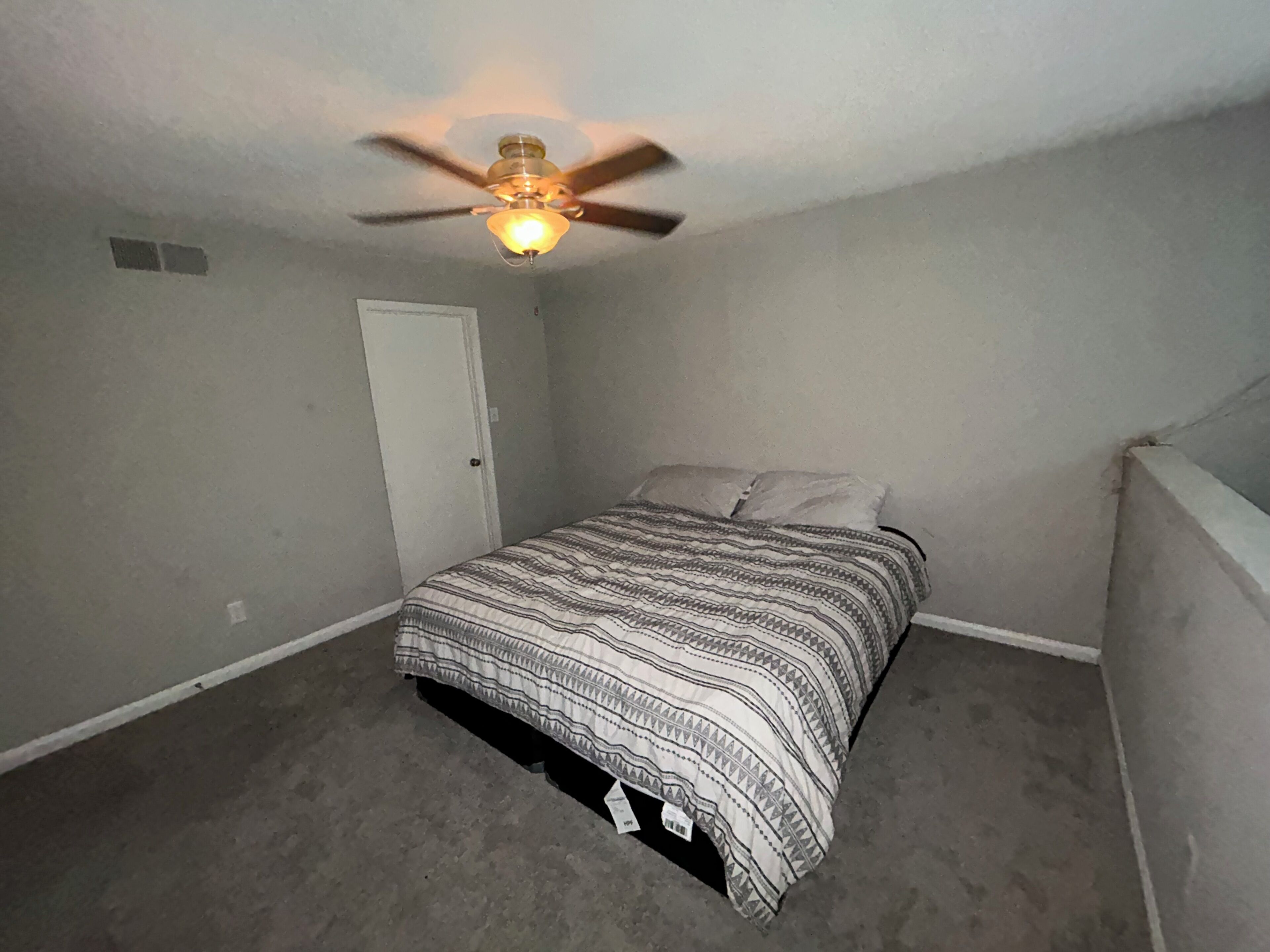 Une chambre à coucher avec un lit, un ventilateur de plafond et une porte.