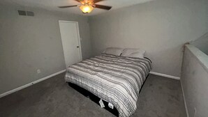 Une chambre à coucher avec un lit, un ventilateur de plafond et une porte.