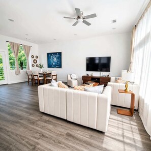 A spacious living room with a sofa, TV, and dining area. - NRG Summer Haven Stay | 3 Stories | Sleeps 6 (Houston)
