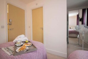 A hotel room with two beds, a tray with breakfast items, and a mirror reflecting a bed and a window. - Beautiful 4 Bedroom House Berkshire - Free Parking (Bracknell)