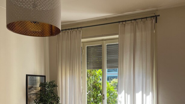 A modern living room with a sofa, a wooden table, a hanging light fixture, a potted plant, and a sliding glass door leading to an outdoor area. - Penthouse 200 sqm 5 min walk from Duomo Milano cathedral. Vip Are sleeps 10 max (Milano)