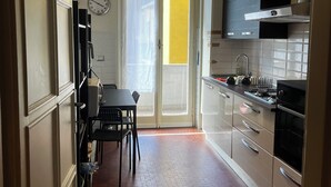 A narrow kitchen with a dining area, a clock on the wall, and a bright yellow wall visible through the door. - Penthouse 200 sqm 5 min walk from Duomo Milano cathedral. Vip Are sleeps 10 max (Milano)