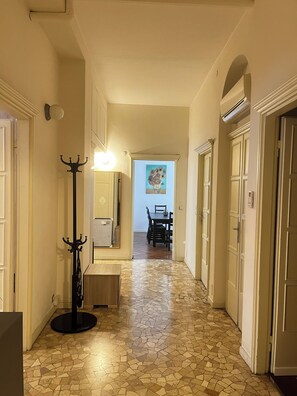 A hallway with a tiled floor, a coat rack, a dining area with chairs and a table, and a painting on the wall. - Penthouse 200 sqm 5 min walk from Duomo Milano cathedral. Vip Are sleeps 10 max (Milano)