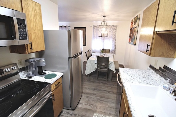 Una cocina compacta equipada con refrigerador, microondas, estufa y cafetera.