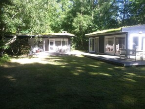 Um imóvel residencial com varanda coberta, gramado e um pequeno deck.
