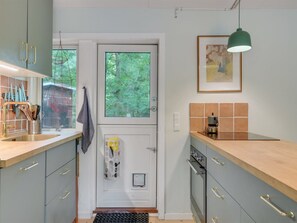 Eine Küche mit Fenster, Spüle, Herd und Schränken.