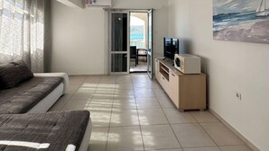 Ein modernes Wohnzimmer mit einer Couch, einem Fernseher und einem Gemälde an der Wand.