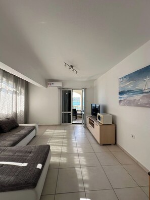 Ein modernes Wohnzimmer mit einer Couch, einem Fernseher und einem Gemälde an der Wand.