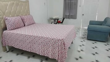 A bedroom with a bed, a chair, a sofa, and a door.