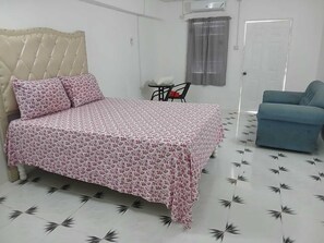 A bedroom with a bed, a chair, a sofa, and a door. - PHS Portland Comfort Stay (Saint Margarets Bay)