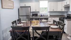 A modern kitchen with white cabinets, a stainless steel refrigerator, a microwave, and a dining table set for four. - Close to Mammoth Cave and other wonderful attractions yet still in a quiet area. (Horse Cave)