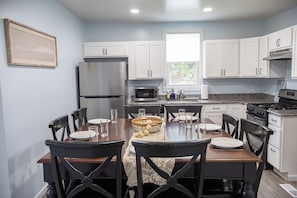 A modern kitchen with white cabinets, a stainless steel refrigerator, a microwave, and a dining table set for four. - Close to Mammoth Cave and other wonderful attractions.  location. (Horse Cave)