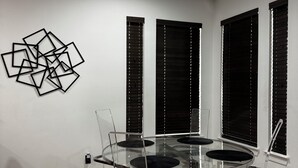 Un comedor con mesa de vidrio, sillas y una lámpara de araña.