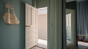 A hotel room with a closed door, a hanging bag, a small table, and a view of the outside balcony. - Casa Bosques Pensión (Mexico City)