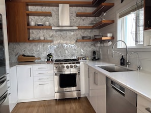 Una cocina moderna con armarios blancos, una estufa de acero inoxidable y un lavamanos con grifo.