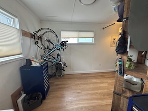 Una habitación con una bicicleta colgada en la pared, un mueble azul para guardar cosas y suelo de madera.