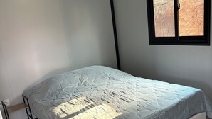 Une chambre à coucher avec un lit, une fenêtre et un plancher en bois.