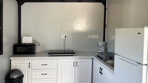 Une cuisine compacte équipée d’un four à micro-ondes, d’un grille-pain, d’une machine à café et d’un réfrigérateur.